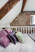 Double bed in the attic bedroom with wooden beams and exposed brickwork