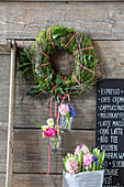 Spring wall decoration with moss wreath and flowers in jars