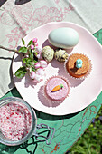 Pink plate with Easter muffins, eggs and sprig of flowers