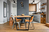 Dining table with chairs in industrial style, kitchen behind it