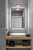 Small minimalistic bathroom, walls and floor covered with large fromat gray stoneware tiles, washbasin