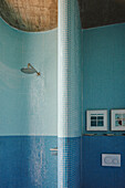 Gebogene Wand mit blauen Mosaikfliesen in der Dusche