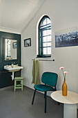 Bathroom with arched glass window, sink, chair and decorative flowers