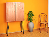 Two door cabinet in copper look, floor vase and classic chair next to it
