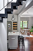 White and grey kitchen with kitchen island, view into dining room, stairs in foreground