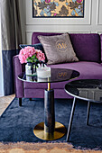 Dark purple sofa with cushions and round coffee tables on blue carpet