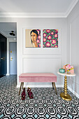 Light grey entrance hall with pink bench, modern art, and geometric floor tiles