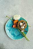Small Easter nest with eggs and ranunculus on turquoise plate