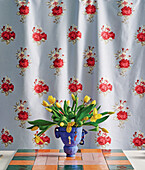 Bouquet of yellow tulips in front of a curtain with a floral pattern