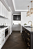 White kitchen with dark Shaker-style wood, gold lantern lighting, and gold hardware