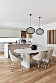 Modern open plan kitchen with coastal style dining area, 80s style column dining table and white upholstered chairs