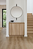 Hall with built-in console table, round mirror, and staircase