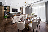 Offener Wohnraum im Hampton-Stil, dunkelbraune Farbpalette mit goldenen Accessoires, Sofa- und Stuhlpolster in kühlem Beige