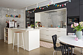 Open-plan kitchen with marble-look backsplash and bunting
