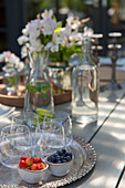 Sommerliche Tischdekoration im Freien mit Heidelbeeren, Kirschen und Blumen