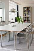 Bright dining area in Scandinavian design, bookcase in the background