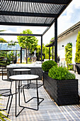 Terrasse mit Pergola, modernen Gartenmöbeln und Bepflanzung