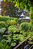 Garten mit Teich, Seerosen und Pavillon im Hintergrund