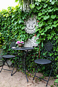 Seating area in the garden with wrought-iron furniture and green plant wall