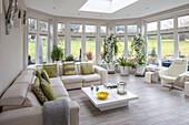 Bright conservatory living room with panoramic windows and plant decorations