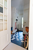 Hallway with chequered tiles and bicycle on the wall