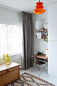 Bright workplace with orange hanging lamp and wooden chest