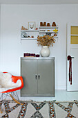 Metal cabinets and white shelves with decoration, orange armchair with fur