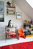 Shelf, children's toys and designer chair in the children's room with sloped ceiling