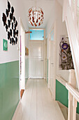 White hallway with green accents, wall busts and pendant light