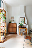 Corner of a living room with retro cupboard, open shelf and houseplants