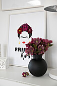 Schwarze Vase mit Blumen vor Frida Kahlo-Bild