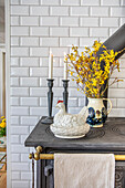 Ceramic chicken and yellow forsythia branches on a black stove