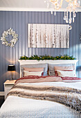 Schlafzimmer mit Doppelbett, Kronleuchter, blauer Wand und Bild