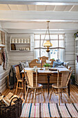 Rustic dining area with wooden furniture and ceiling lamp in a white-paneled room