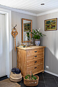 Wooden chest of drawers with mirror and decorative objects in a bright hallway