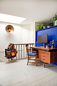 Home office with wooden desk in front of blue wall and plants