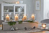 Advent chandelier with candles and fir branches on wooden table in dining room