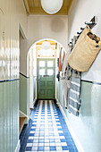 Hallway with blue and white tiled floor and coat rack on the wall