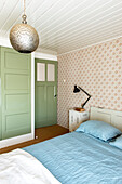 Bedroom with green door and patterned wallpaper