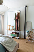 Clothes rack and mirror in bedroom with natural fibre carpet