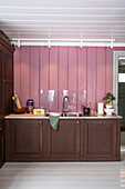 Küchenzeile mit dunkelbraunen Schränken und rosa Wandpaneelen