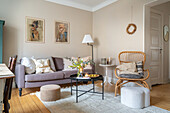 Wohnzimmer mit Sofa, Rattansessel und Kunst an der Wand