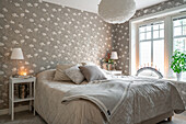 Bedroom with floral wallpaper and light-colored bed linen