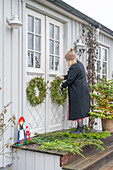 Woman decorates white front door with wreaths