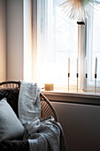 Armchair with fur, blanket and pillow, candles on windowsill