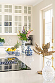 Light-colored kitchen with floral arrangement and fruit bowl