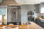 Modern kitchen in grey with stainless steel appliances and wooden countertop