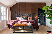 Upholstered bed in front of wooden wall in the bedroom