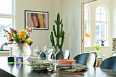 Dining table with colourful flower arrangement and cactus in the background