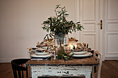 Table setting with olive branches in a vase